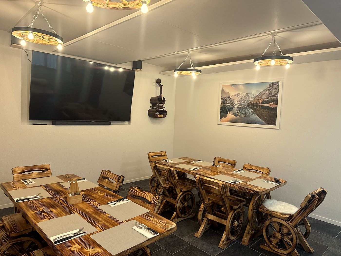 La salle du bas avec ses tables en bois et le grand écran